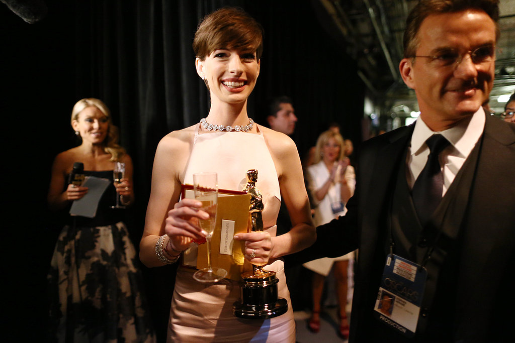 Anne Hathaway juggled her Oscar, a glass of champagne, and her winning envelope backstage after her win.
Anne Hathaway juggled her Oscar, a glass of champagne, and her winning envelope backstage after her win.