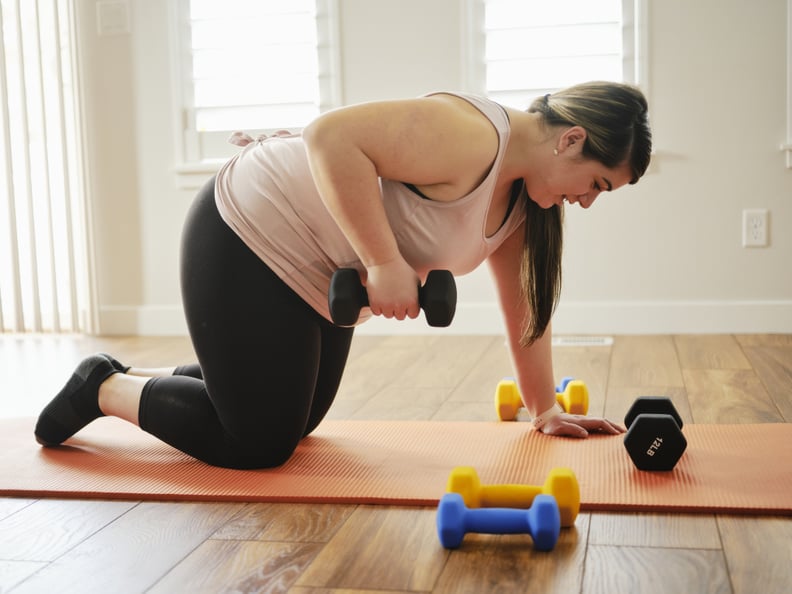 A woman exercising in her home with hand weights.