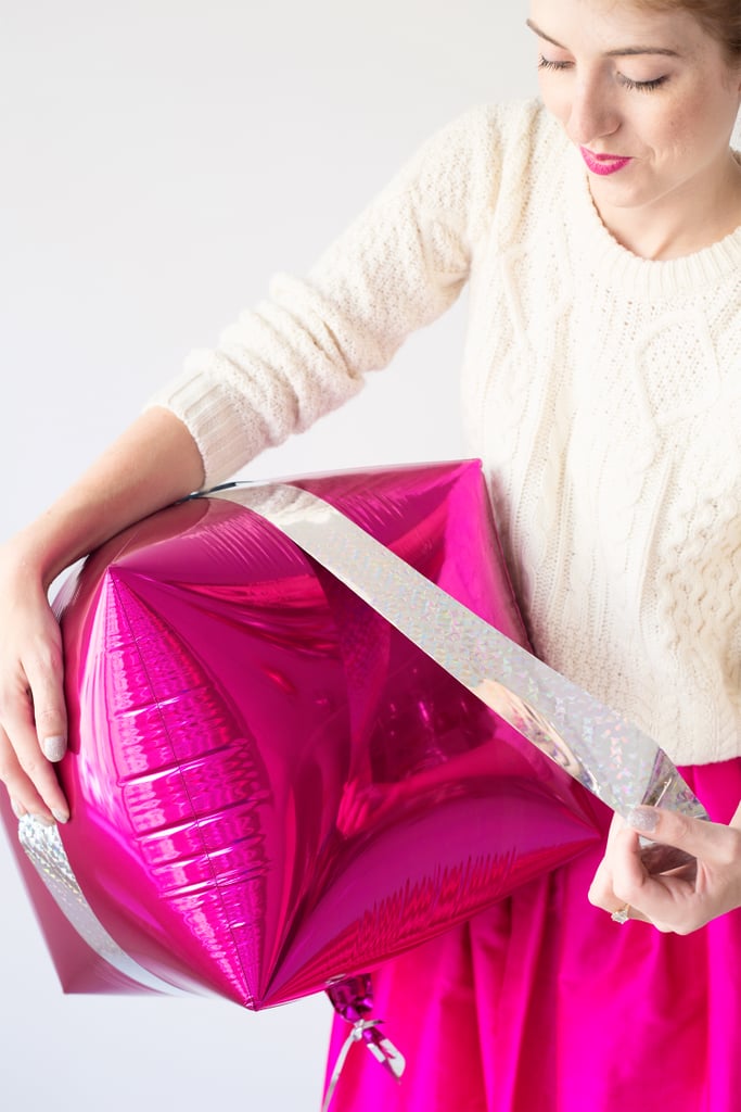3. Repeat these steps on the other sides of the balloon so there is a ribbon running down all four sides.
4. Finally, remove the protective backing on the adhesive on your bow and stick it right on top of the balloon. It is important, as stated in the supply list, that the bows be no larger than about 3 1/2 inches for the balloon to float properly. This is the size of a standard holiday bow!