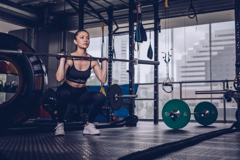 Young fitness woman exercise with barbell in gym