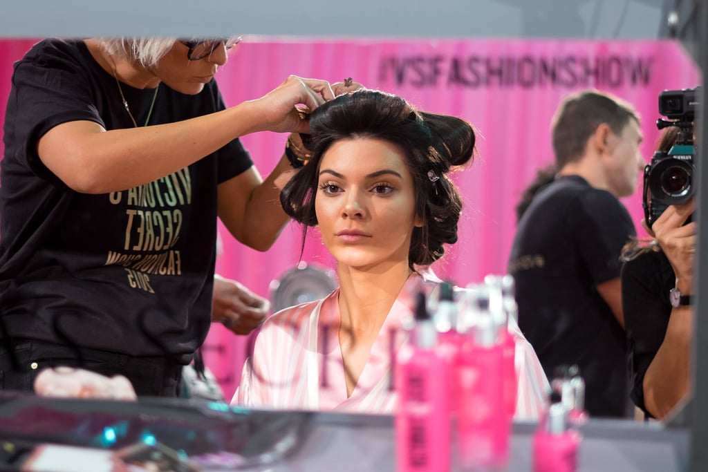 Kendall Jenner looks at her flawless skin as she gets her hair tucked into rollers.