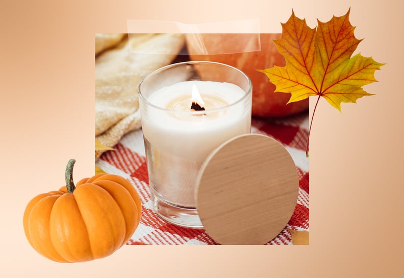 A white candle situated between a pumpkin and fall leaf.