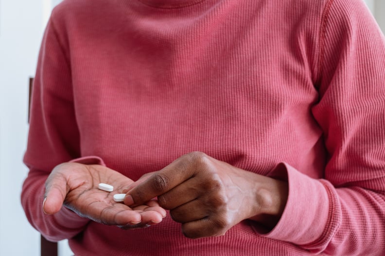 Woman holding pills in palm of her hand, wondering if it's OK to take ibuprofen every day.