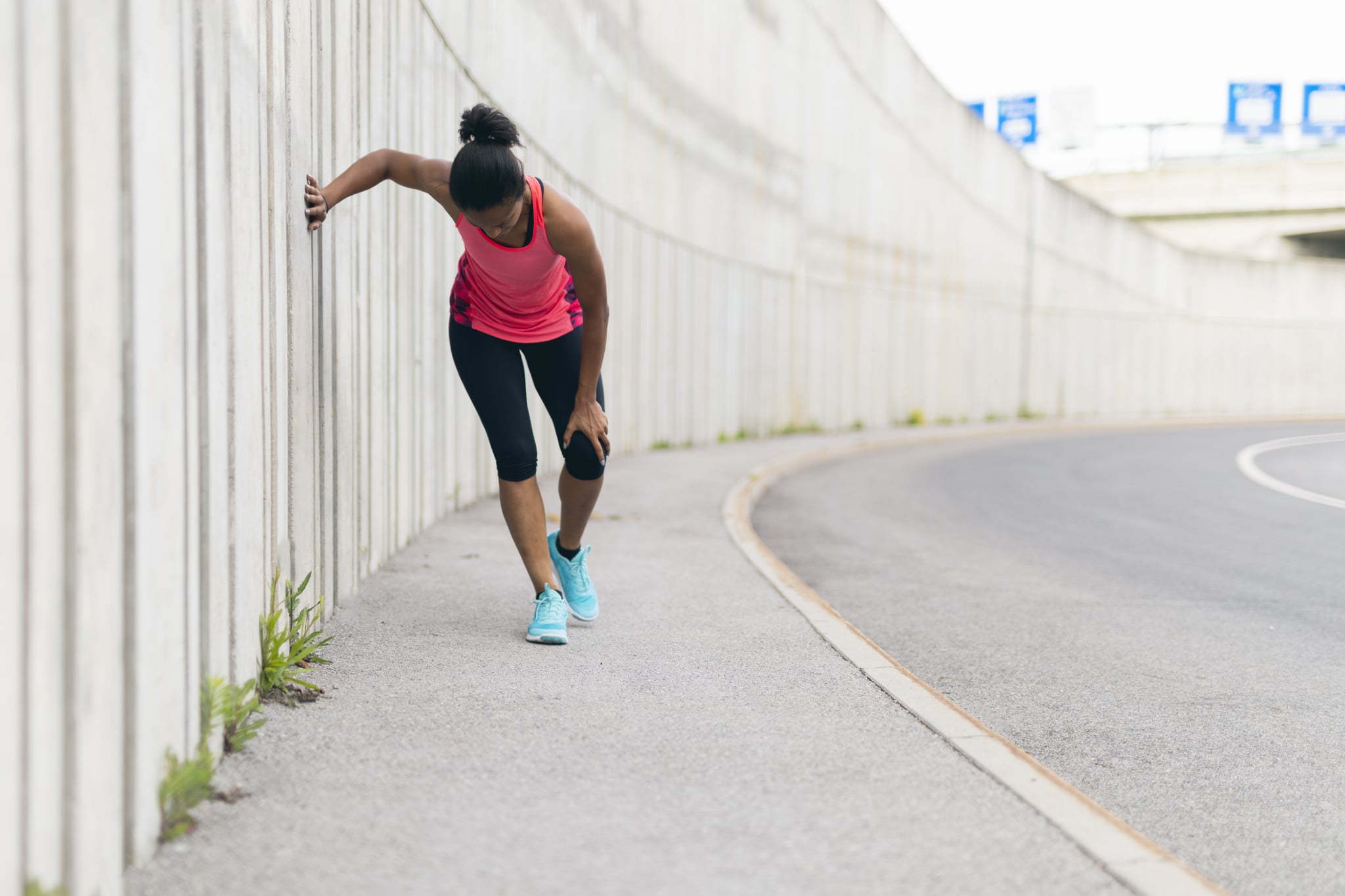 Young woman taking a break from running, having a knee injury