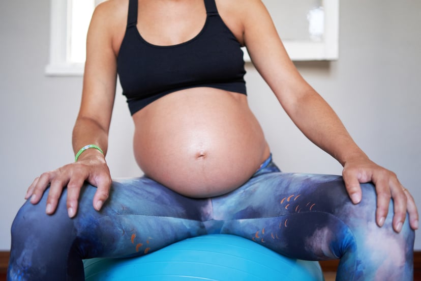 Front view of pregnant woman sitting on gymball doing pilates exercises for pregnant women.
