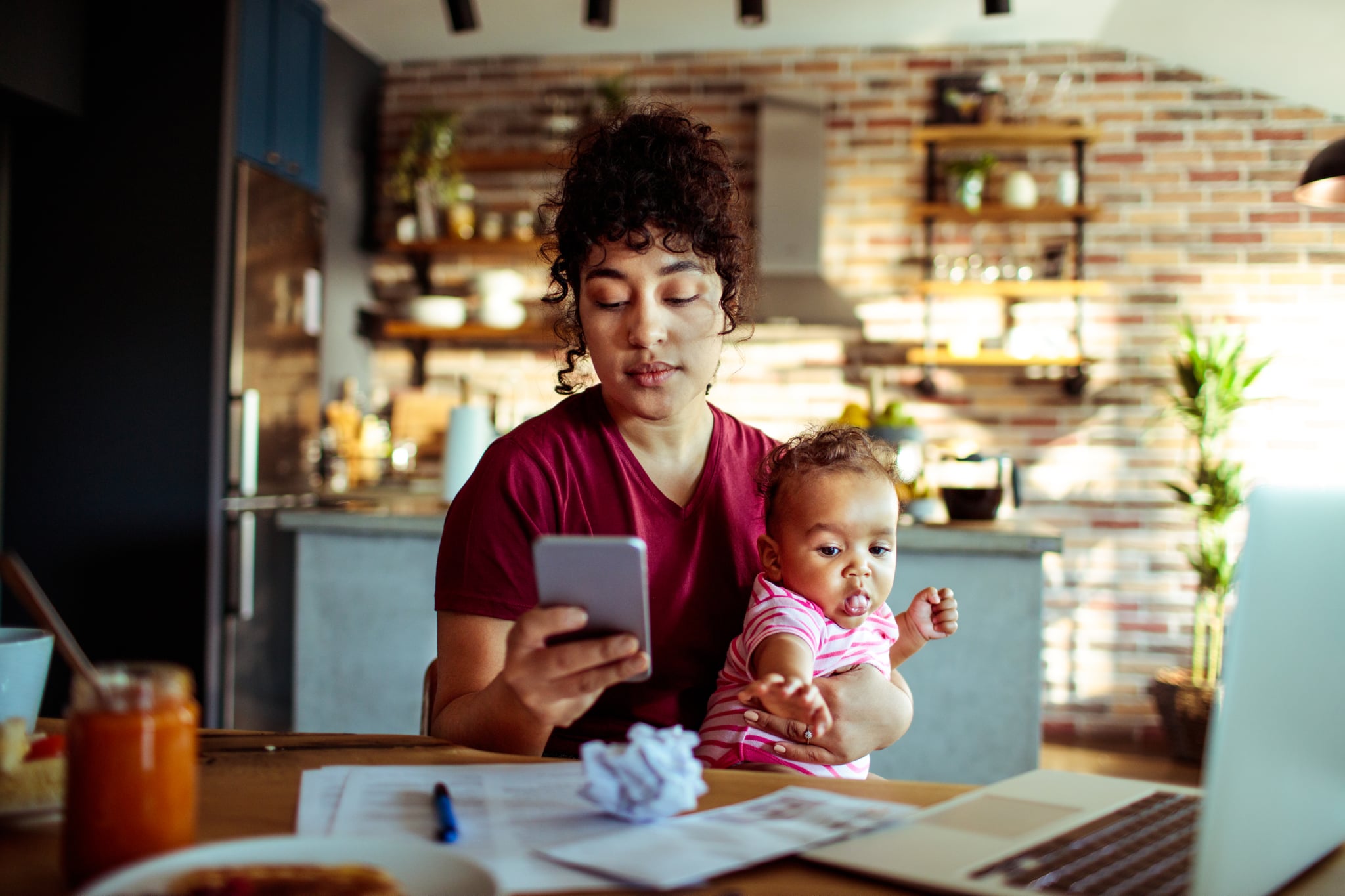 Close up of a mother using a phone with her daughter while having breakfast and doing bills