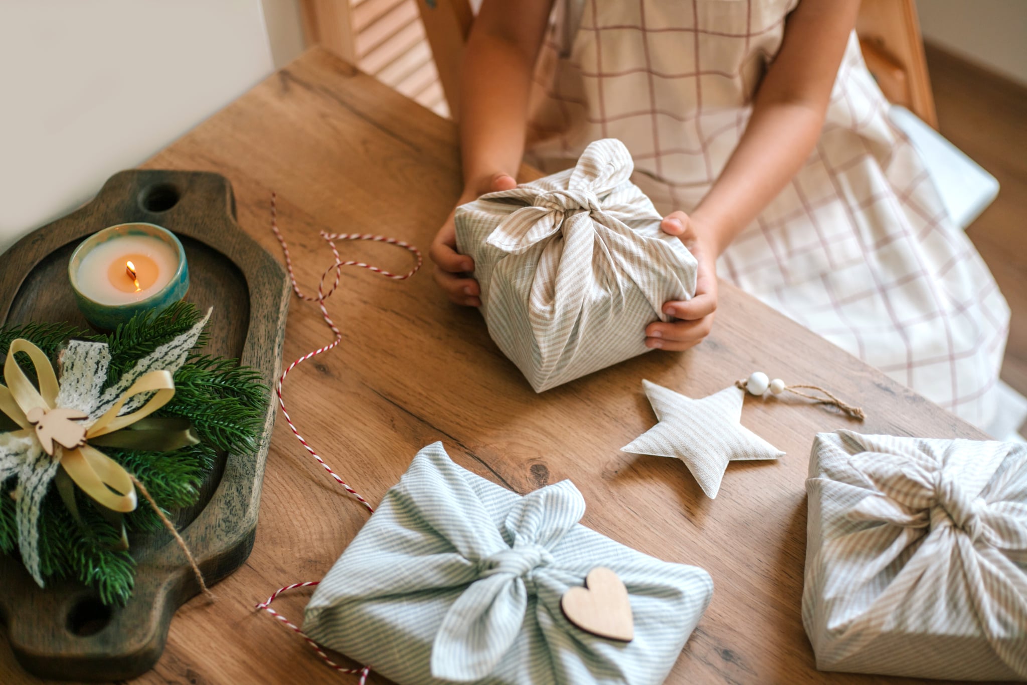 Close up child's hands holding Christmas furoshiki gift. Zero waste Christmas concept.