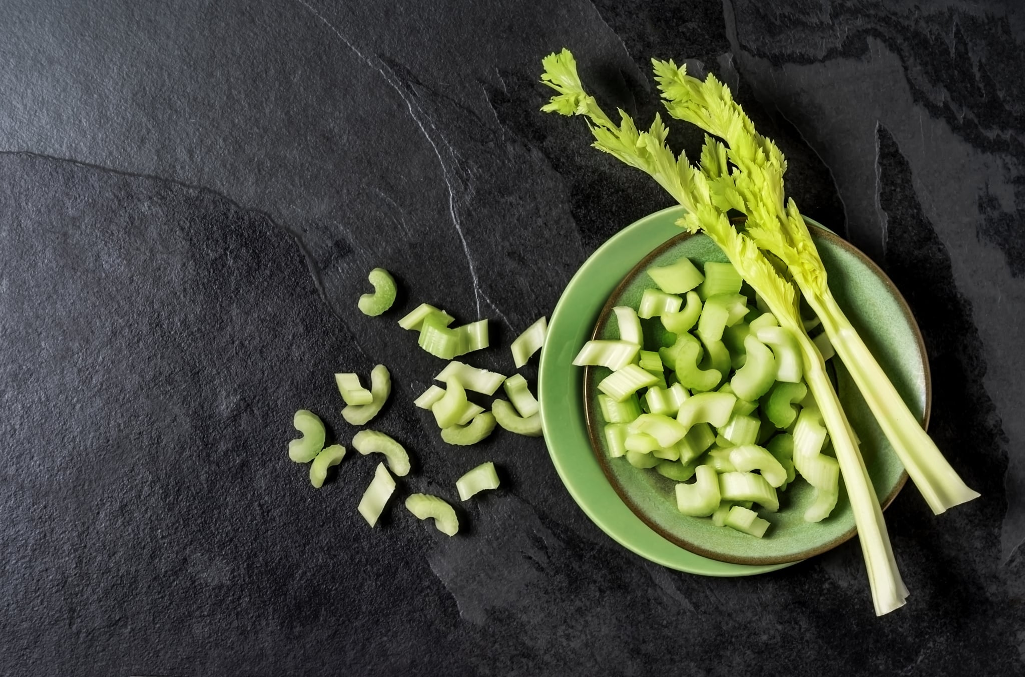 Celery stalks on a plate on black background