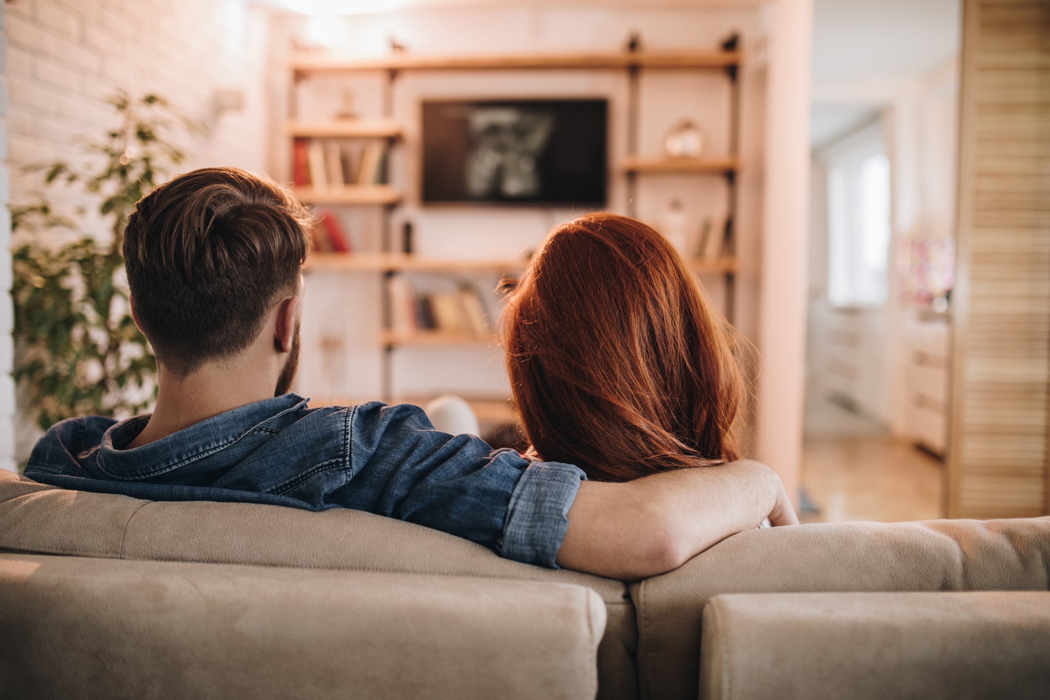 Behind the Back View of Couple on Couch Watching TV