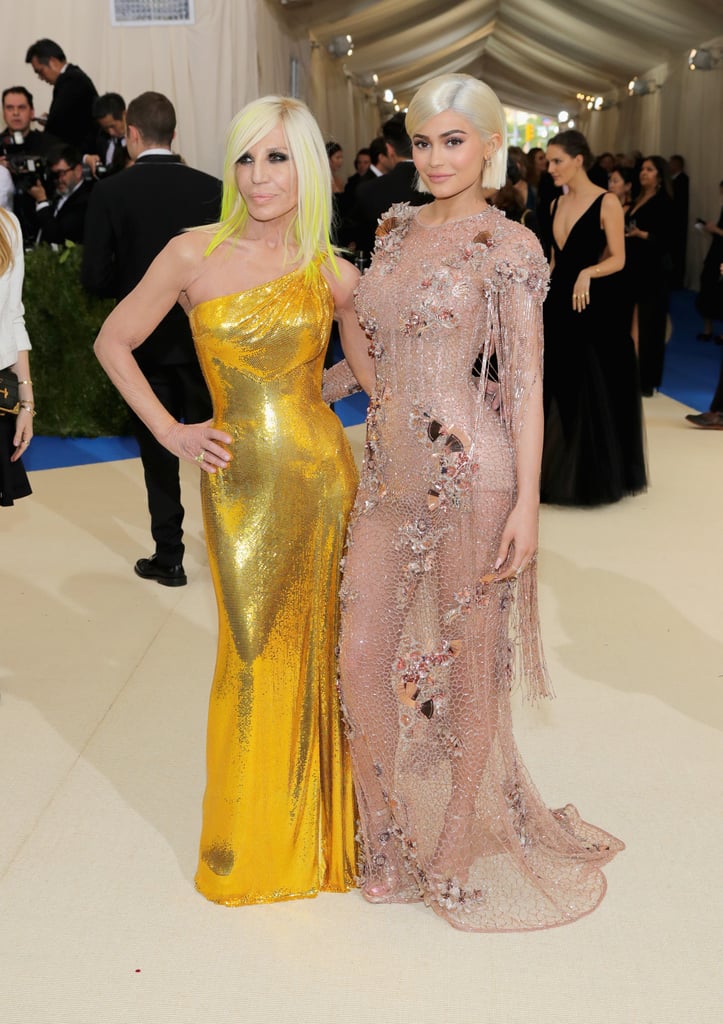 Both Kylie Jenner and Donatella Versace are known for their love of glamour and we couldn't wait to see what both women decided to wear for the 2017 Met Gala. Naturally, they did not disappoint, stepping out in glimmering Versace gowns.
Kylie wore a floor-length variation of a naked dress, made with nude, sheer, mesh material. The shimmering gown was adorned with beads and sequins and included one long sleeve and one short sleeve with tassels hanging from her arms. She paired the look with a blue and gold clutch. 
Donatella went in a different direction and stepped out in a yellow-sequined, asymmetrical Versace dress reminiscent of a disco ball.
Keep reading to see all the photos of the pair.