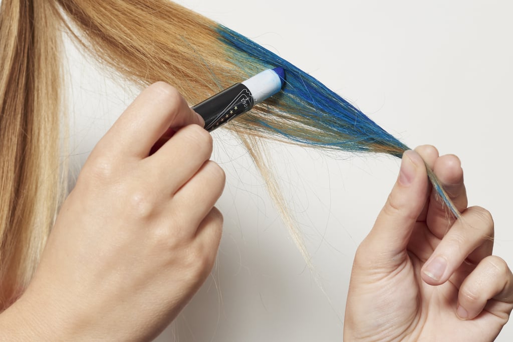 Firmly grasping your left ponytail by its tip, color your hair from the halfway point down with the blue chalk. Blend the line of demarcation with your fingers to create an ombré effect.