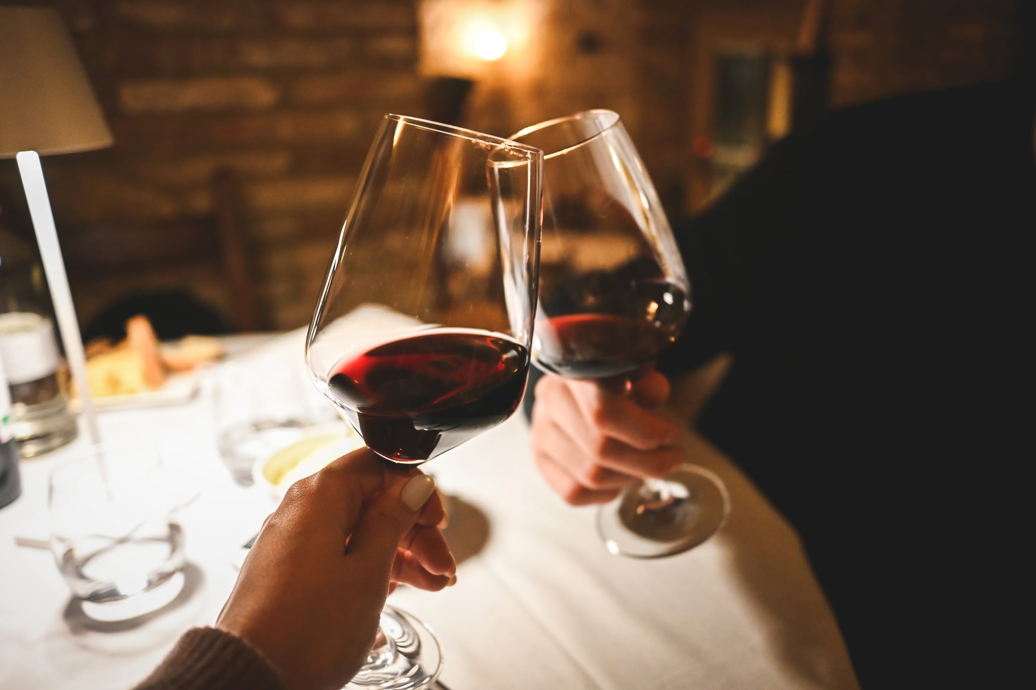 Couple on a Date Touching Red Wine Glasses Together As They Cheers