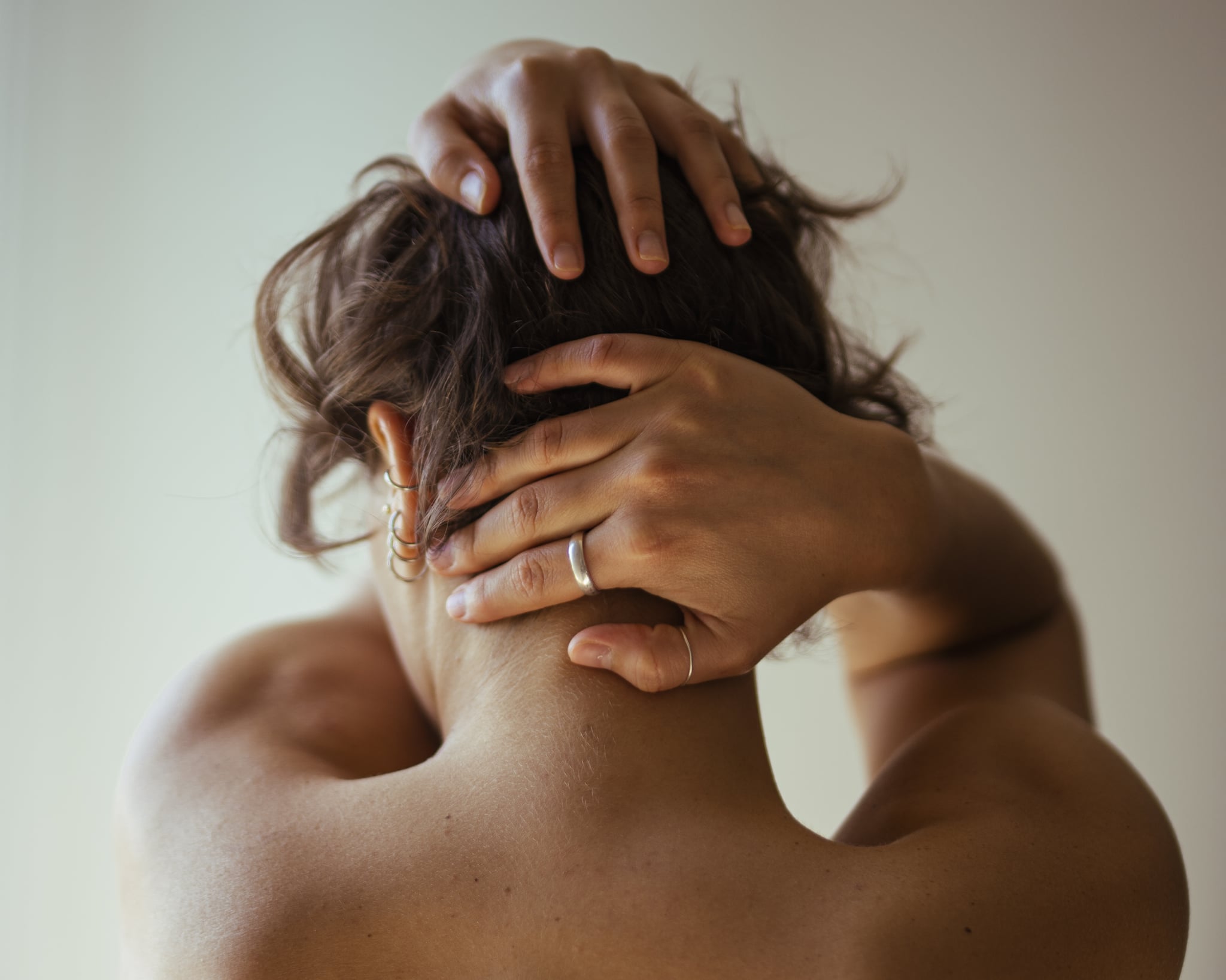 Woman touching her bare neck, one of the erogenous zones, from behind.