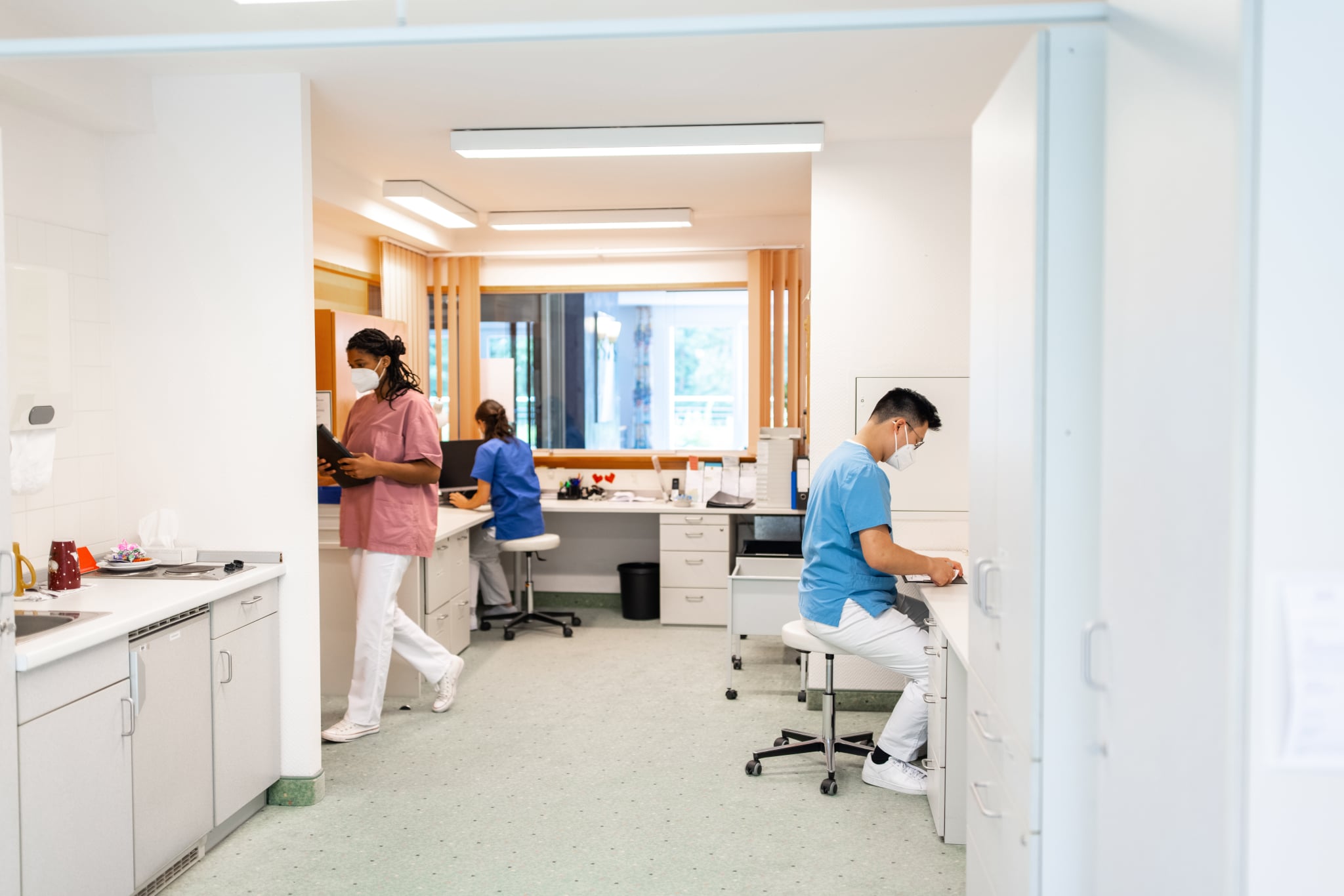 Male and female staff working in hospital administration department. People in uniform and face masks working in clinic during pandemic.
