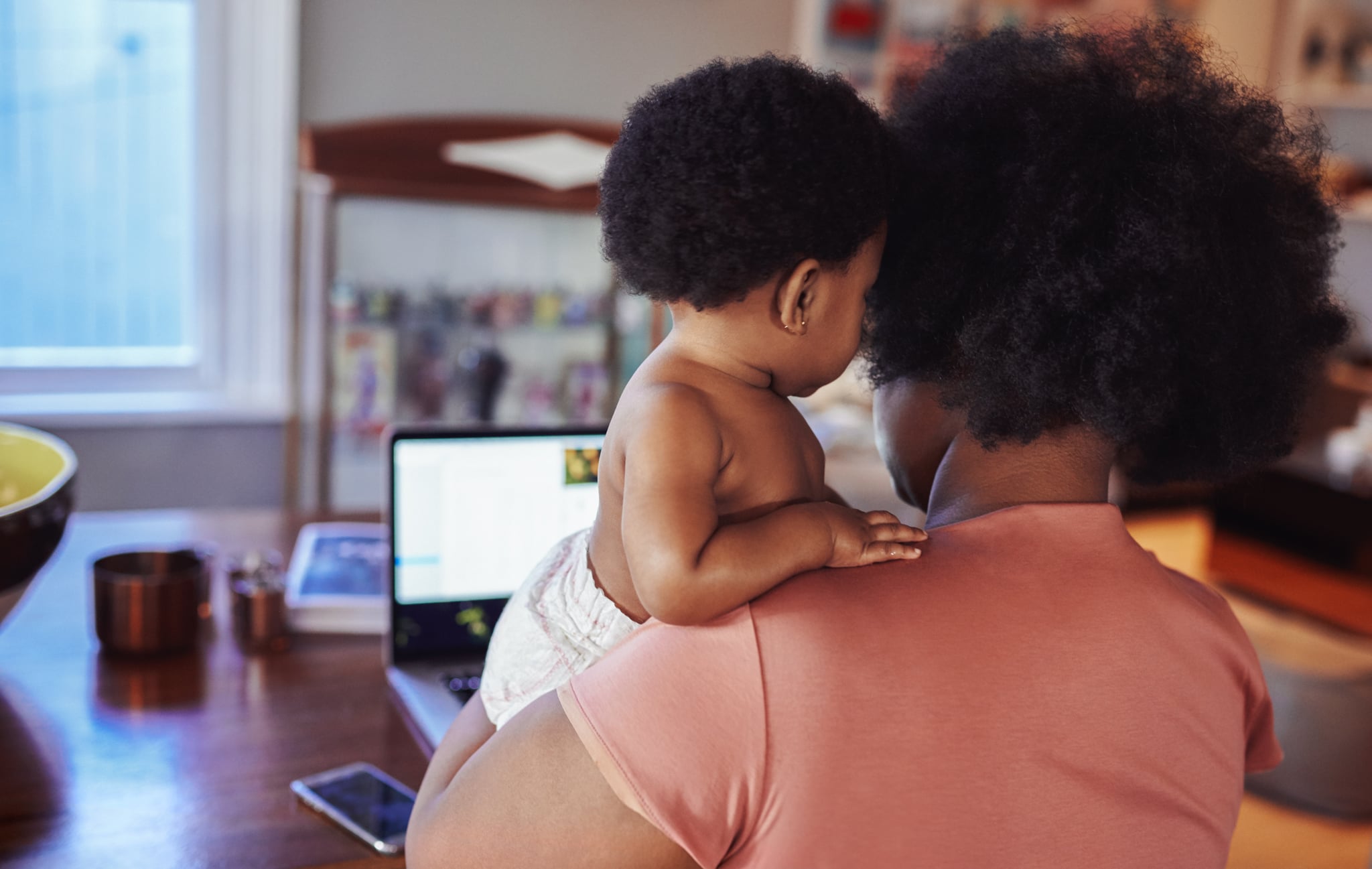 Mom on her laptop working while holding her baby