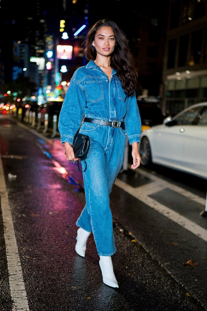 Shanina Shaik styling a denim jumpsuit with white boots.