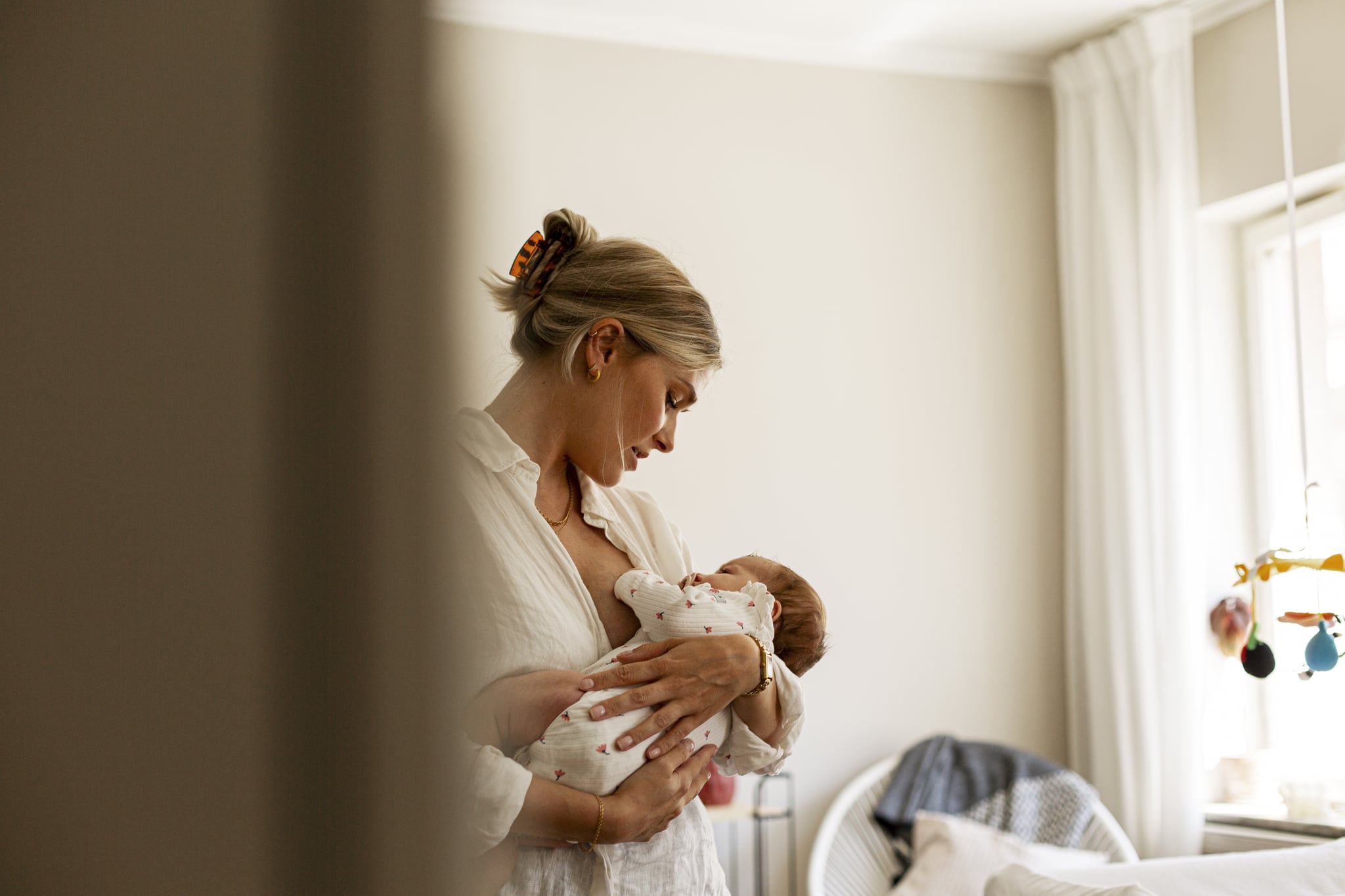Mother breastfeeding son while standing at home