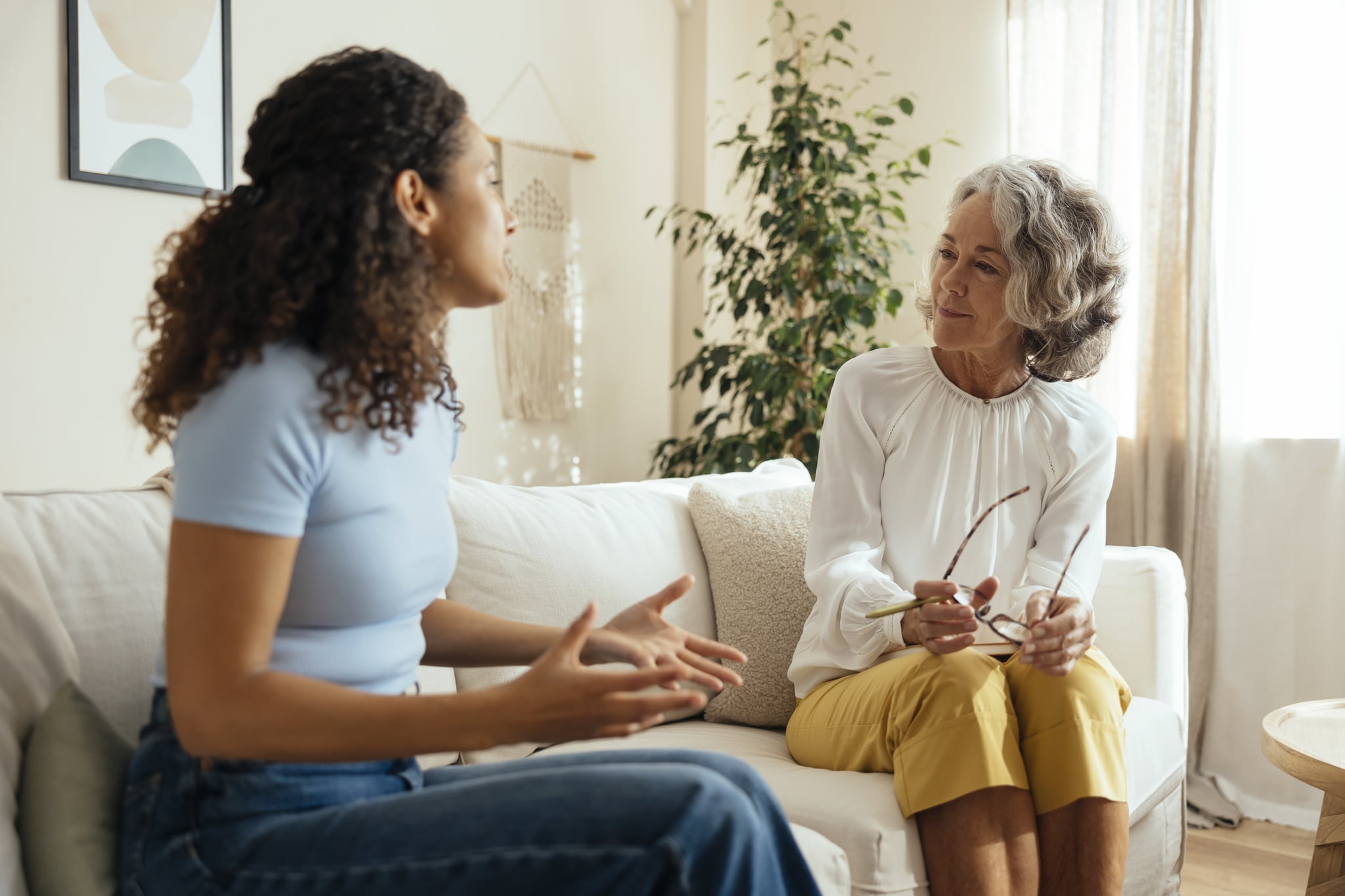 Woman in therapy, sitting on the couch and talking to her therapist in person.