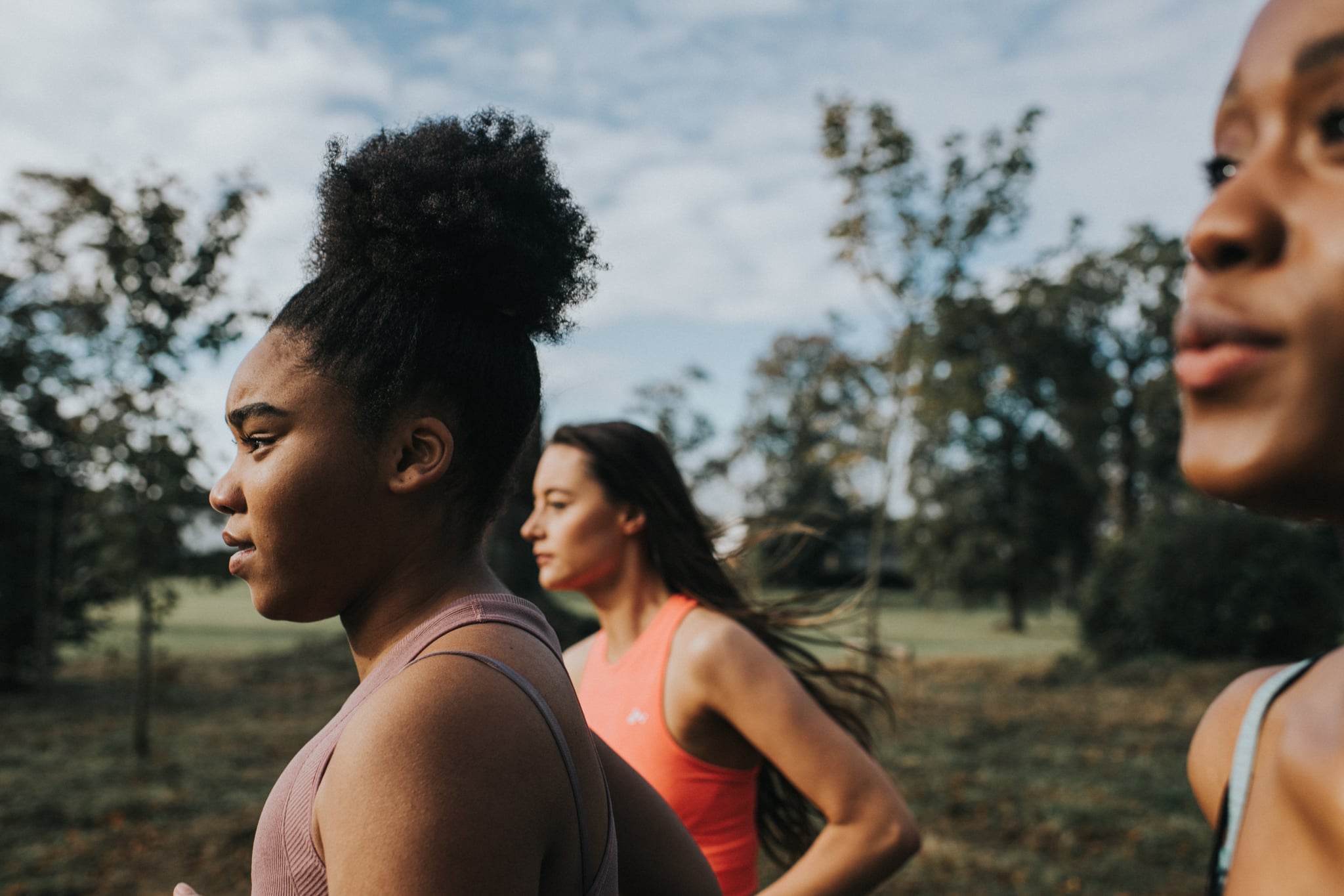 Woman joggers, running through a sunny park at sunrise. 