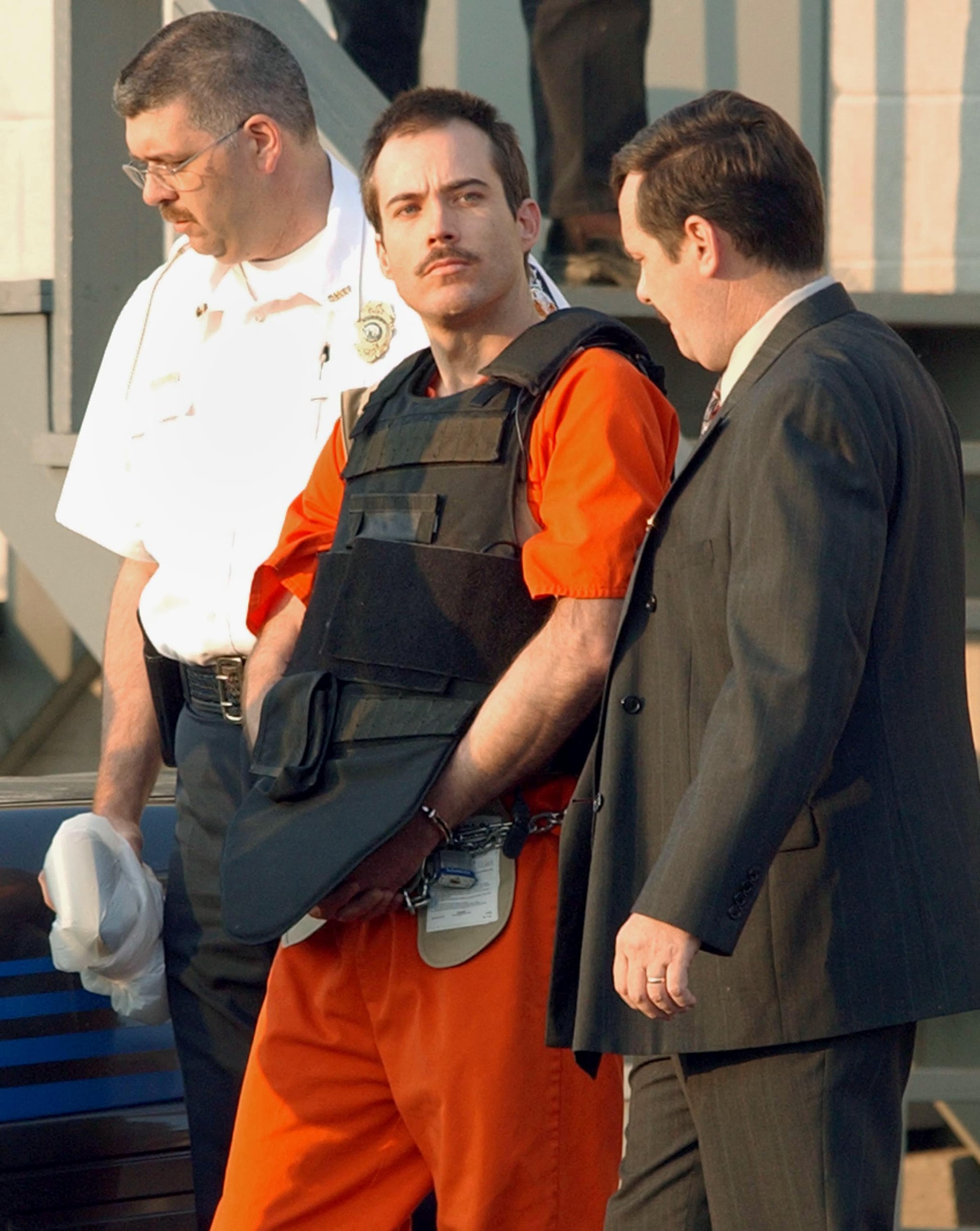 MURPHY, NORTH CAROLINA - JUNE 2: Multiple bombing suspect Eric Robert Rudolph (C) is escorted by law enforcement officials from the Cherokee County Courthouse and Jail in Murphy, North Carolina, June 2, 2003 to a Federal court hearing in Asheville, North Carolina. Rudolph is a suspect in at least three bombings, including the 1996 Olympic Park bombing in Atlanta. (Photo by Erik S. Lesser/Getty Images)