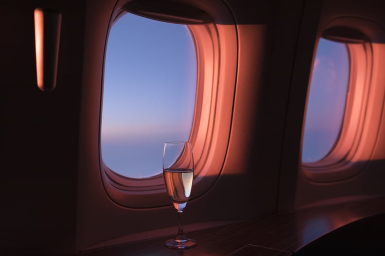 A glass of champagne at a first class window seat during sunset.