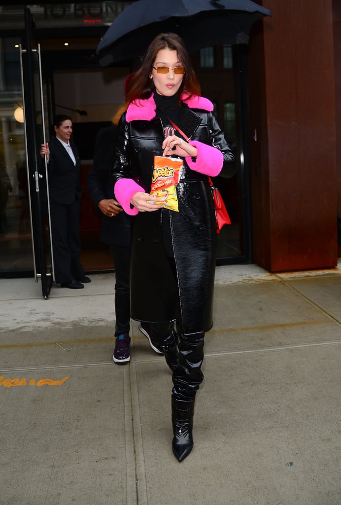 Enjoying a bag of Flamin' Hot Cheetos while wearing a black patent leather coat with pink furry accents. She finished her look off with Alchimia Di Ballin's Daphne puffer booties and a Prada bag.