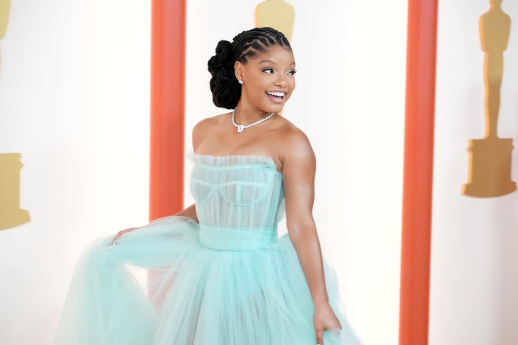 Despite portraying Ariel in Disney's live-action version of "The Little Mermaid," Halle Bailey dressed like a different princess for the 2023 Oscars. On March 12, the actor-singer arrived on the red carpet in a showstopping tulle dress resembling Cinderella's ballgown. With a corset bodice and sheer panels, the sweeping number came in a beautiful shade of sea blue, likely a nod to the onscreen mermaid's turquoise tail. 
"I was really excited to wear this beautiful dress to go into the fairytale world and give them a princess for one day," Bailey said in an E! red carpet interview. She leaned toward simple accessories, wearing matching blue heels and a diamond statement necklace, to highlight the striking gown. Her stylist Nichole Goodman described the starlet's dress as a "soft launch" for what's to come in the "The Little Mermaid" press tour, according to E!
Bailey, who's presenting an award during the show, joined other glamorous stars on the red carpet, including Cara Delevingne in a red one-shoulder slit dress, Florence Pugh in a unique mullet dress, and Ana de Armas channeling Marilyn Monroe in a sparkly white gown. 
See more photos of the Disney princess's look from all angles ahead.

    Related:

            
            
                                    
                            

            Laverne Cox&apos;s Oscars Nails Perfectly Mirror Her Gown