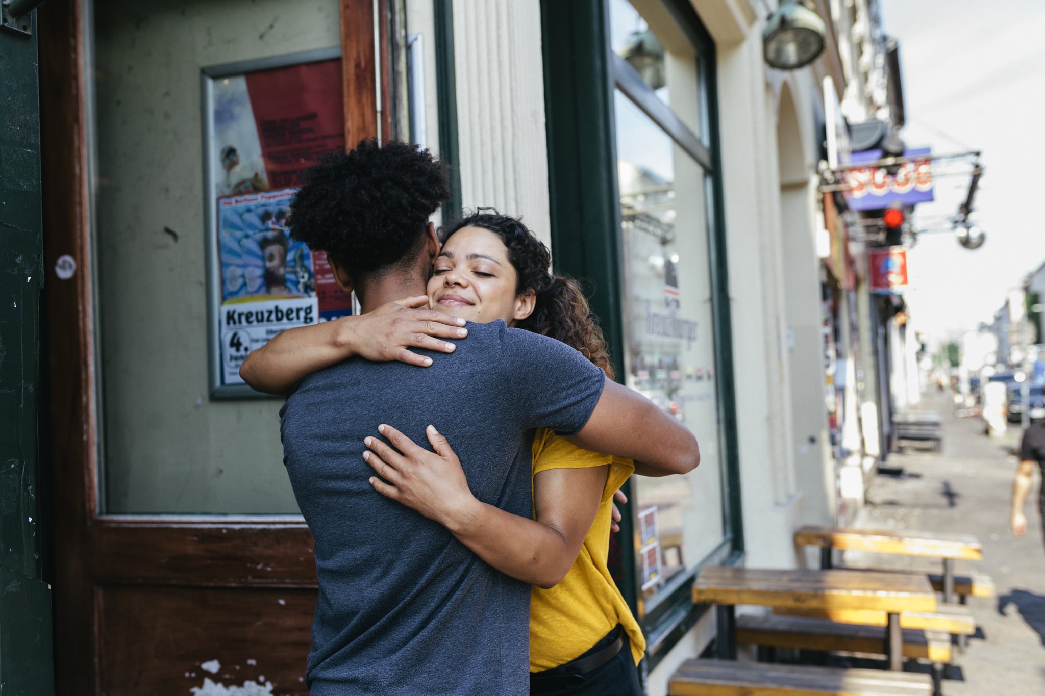 A couple of friends ebracing each other outside a burger restaurant.