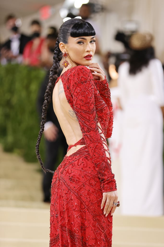 Megan Fox's comeback year is now complete with an appearance at the Met Gala. Just one day after attending the MTV VMAs in a headline-making Mugler dress, the actress arrived at the star-studded event in an expectedly sexy Dundas gown featuring a high slit and various criss-cross cutouts. She paired the red dress with matching platform sandals, statement earrings, and a blunt bangs hairstyle. 
It's not currently super clear how the outfit — created by a Norwegian designer — fits the Americana theme, but, really, is there anything more American than Megan Fox on a red carpet? "It's on an American girl", Megan told Keke Palmer in a Vogue livestream interview. Browse photos of the hot look ahead.

    Related:

            
            
                                    
                            

            Whew, These Met Gala Beauty Looks Were Worth the Wait