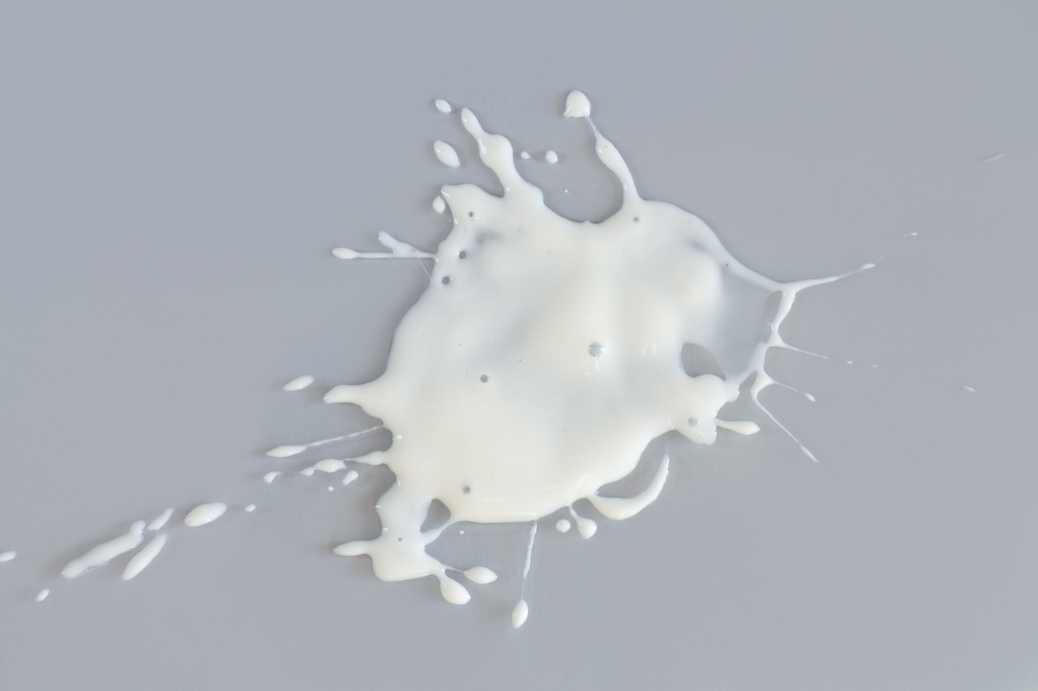 Splash of spilled white liquid on gray background top view