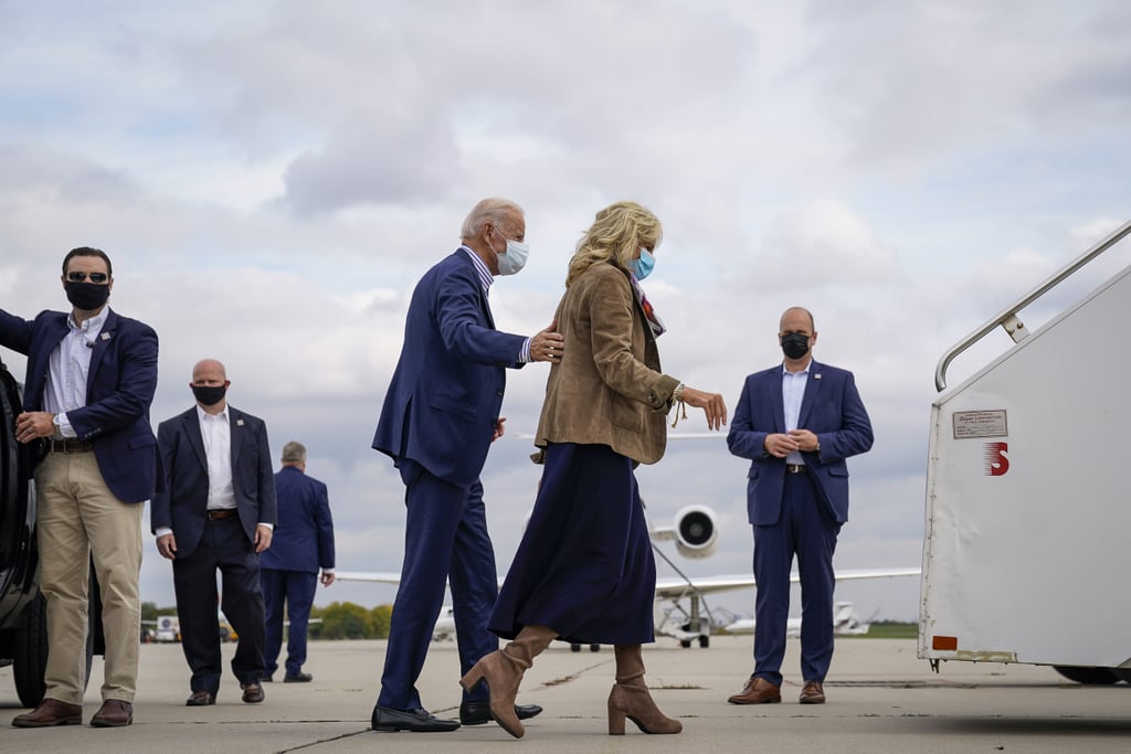 Back in October 2020, Dr. Biden boarded the campaign plane in Philadelphia wearing a navy midi dress that revealed just the right amount of boot, coordinated with a matching suede camel blazer and graphic-printed scarf.