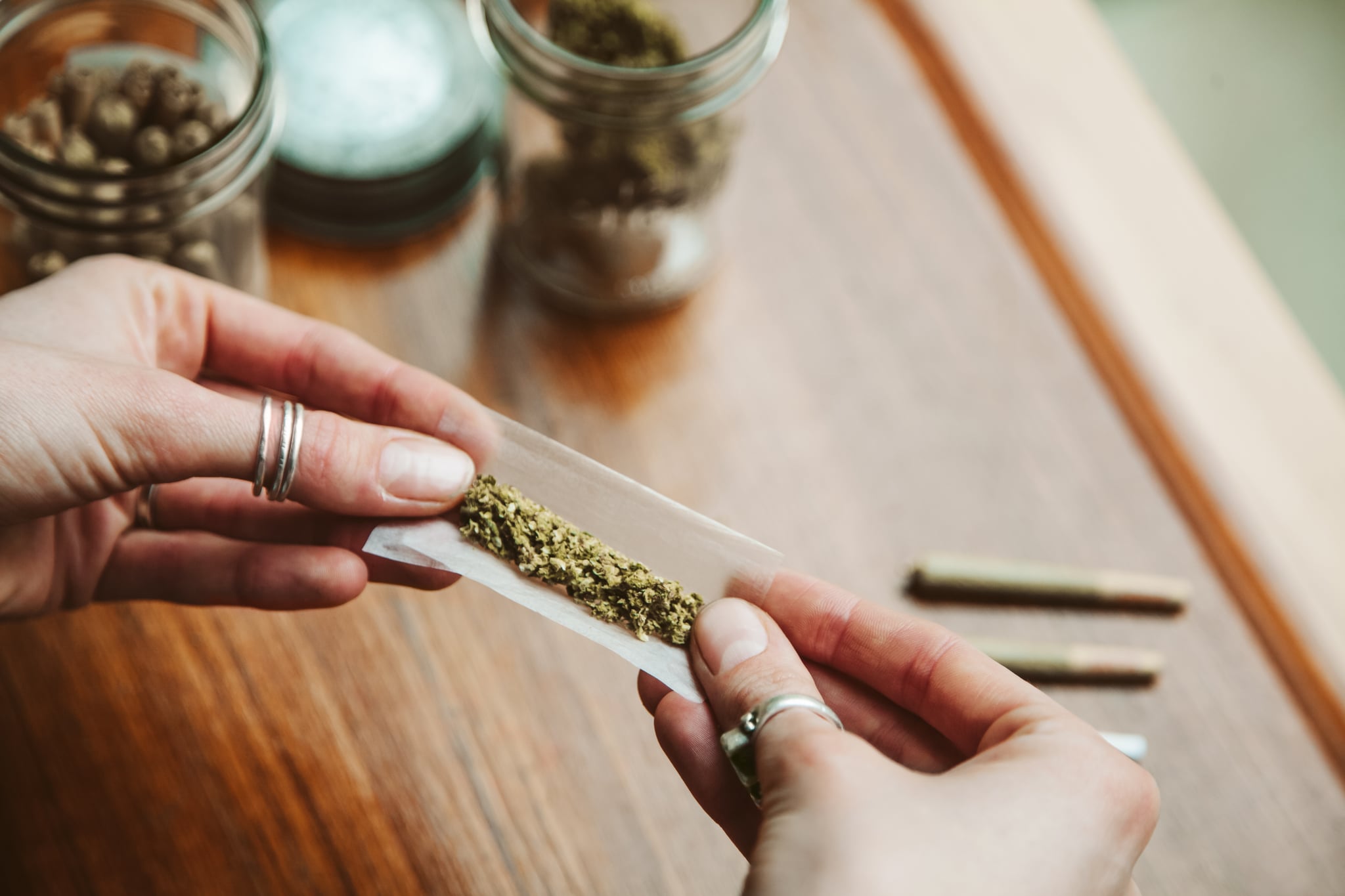 Hands making cannabis joint at marijuana shop