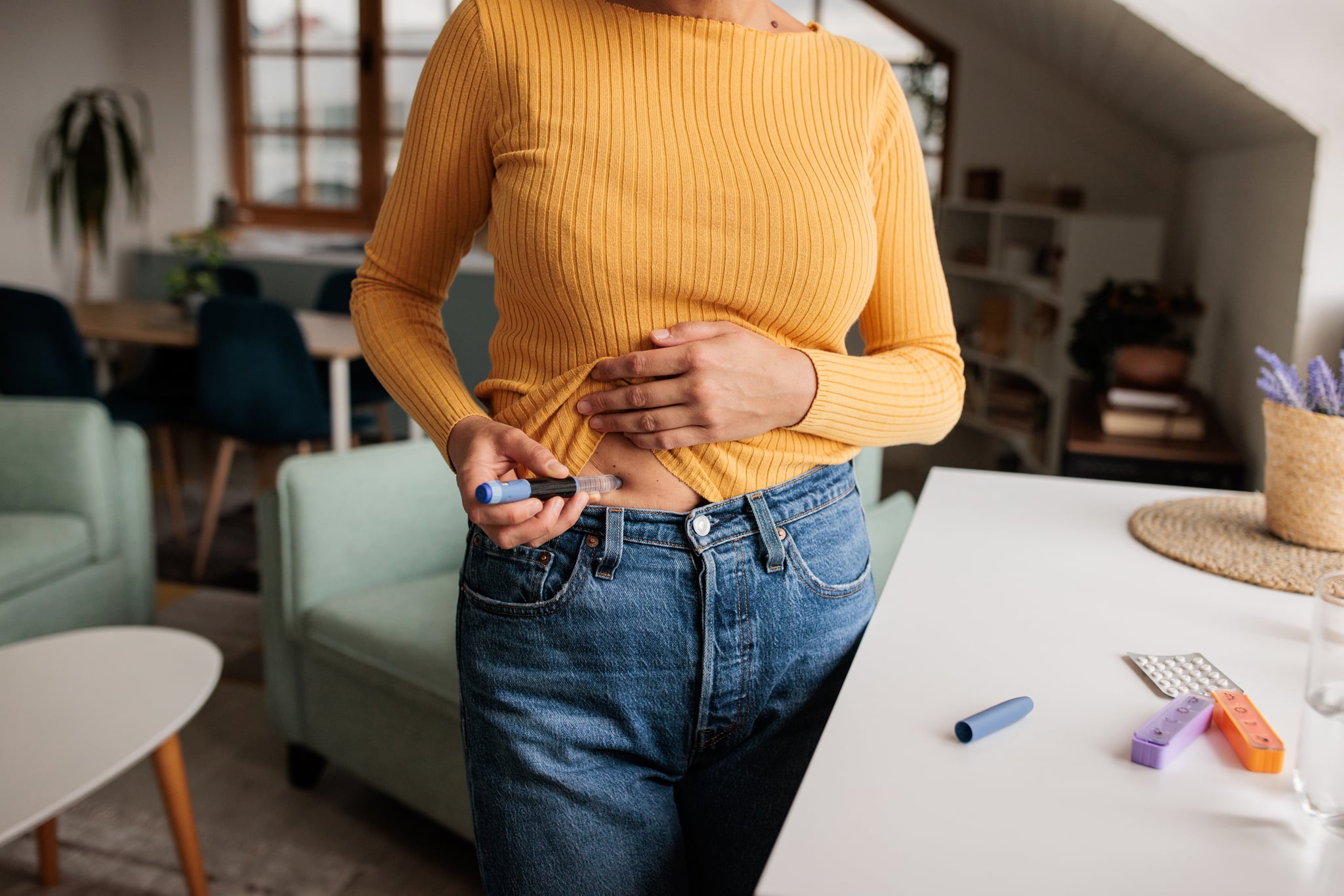 Woman applies an IVF treatment injection to her stomach while at home.