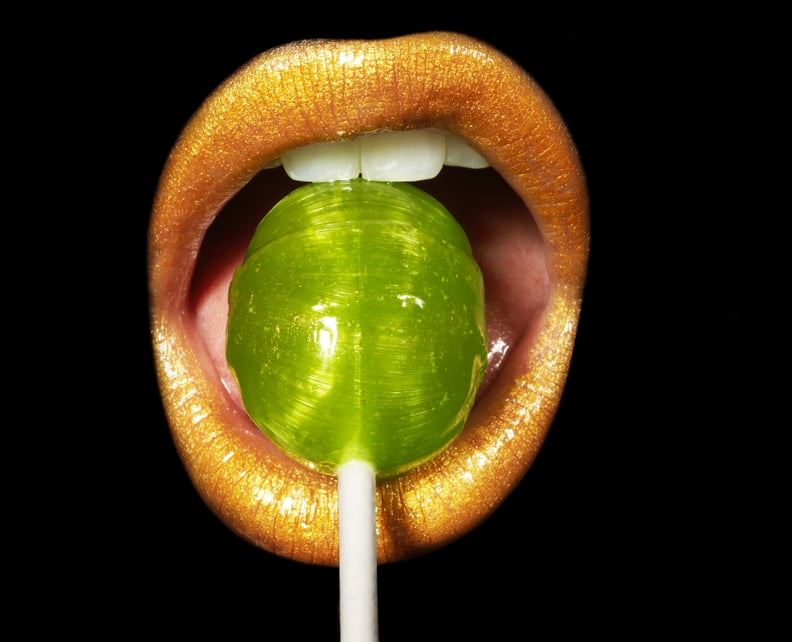 金色的嘴唇在绿色棒棒糖来模拟如何口交