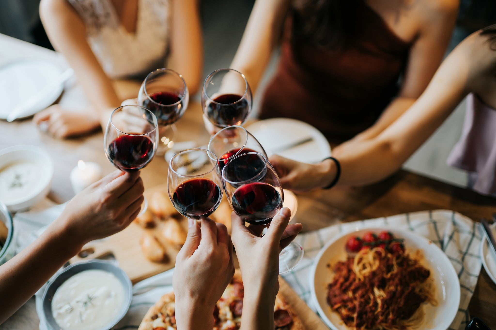 Close up of happy young friends having fun and toasting and celebrating with red wine during party