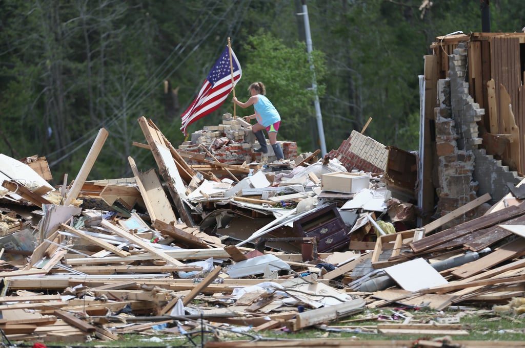 A young girl placed an American flag on the rubble of her grandparents' house after it was destroyed by a tornado in Louisville, MS.