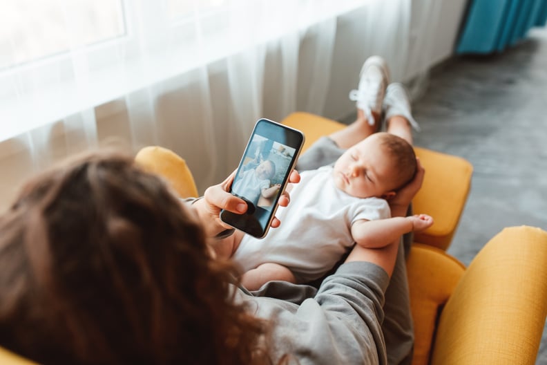 mother takes a photo of her newborn baby on a smartphone. family memories.