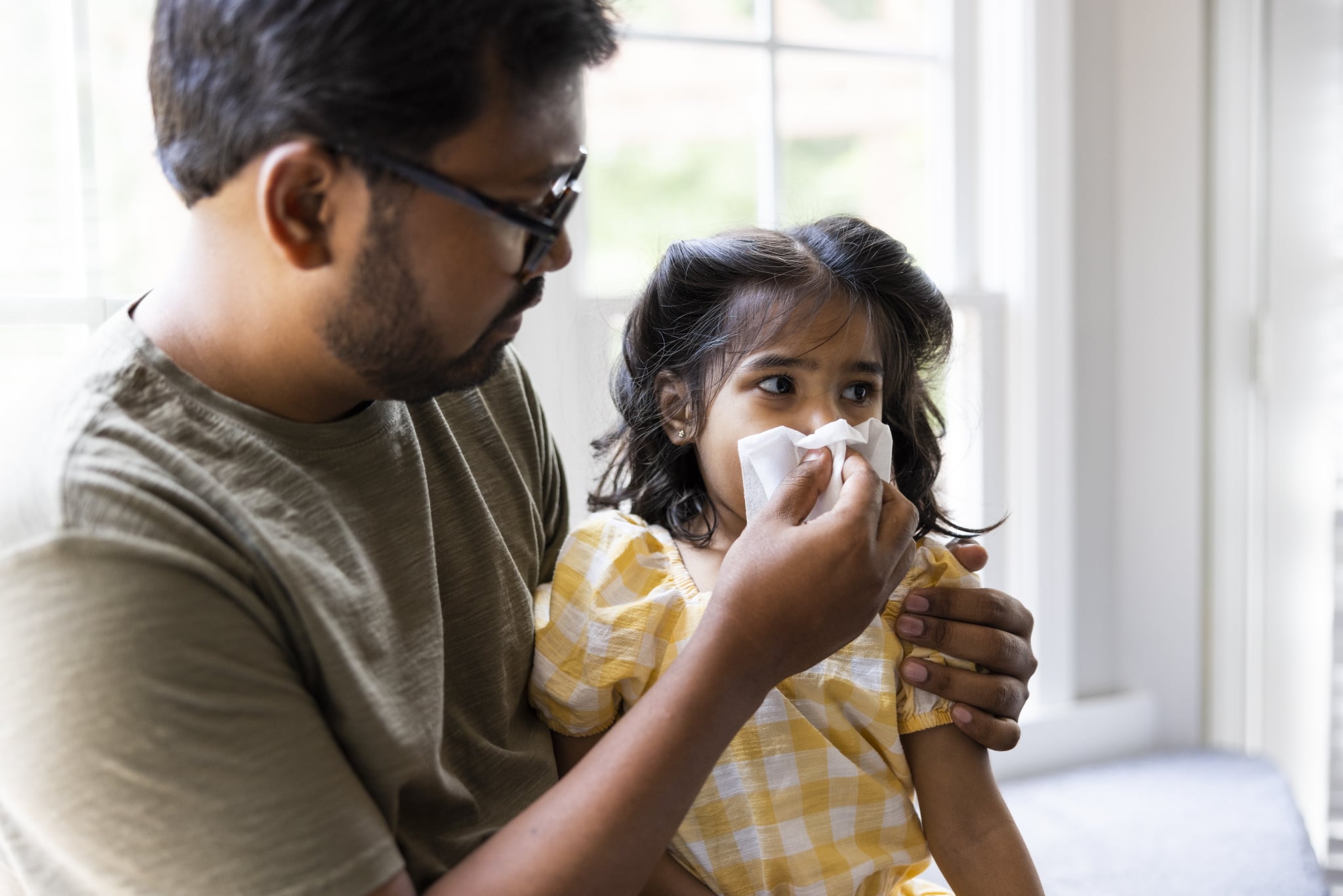 Father wiping toddler daughters nose