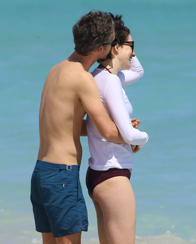 Anne Hathaway sealed her Sunday fun day with sweet kisses from husband Adam Shulman, frolicking in the sand as they took in the warm weather in Miami Beach, FL.