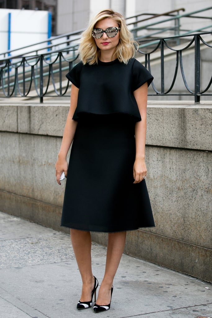 When you have a highly structured black dress, streamlining the rest of the look — black-and-white heels and tortoiseshell cat-eye sunglasses — keeps the attention where you want it.