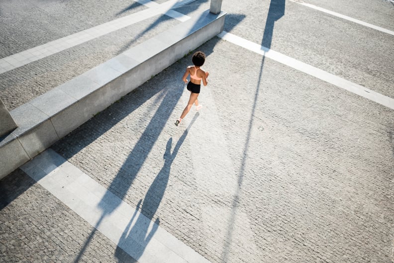 Fit sporty model running on city road. Top view captured.