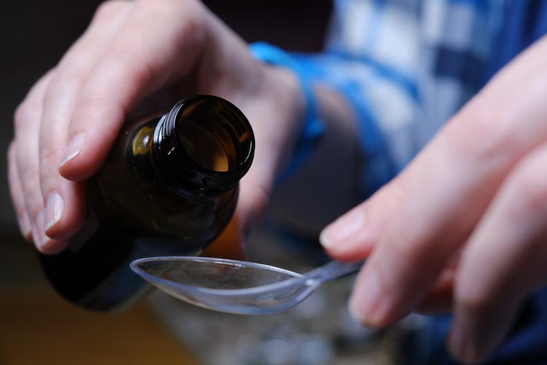 Human hands are taking medicine syrup with measuring spoon