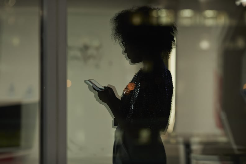woman checking her phone in a dimly light office
