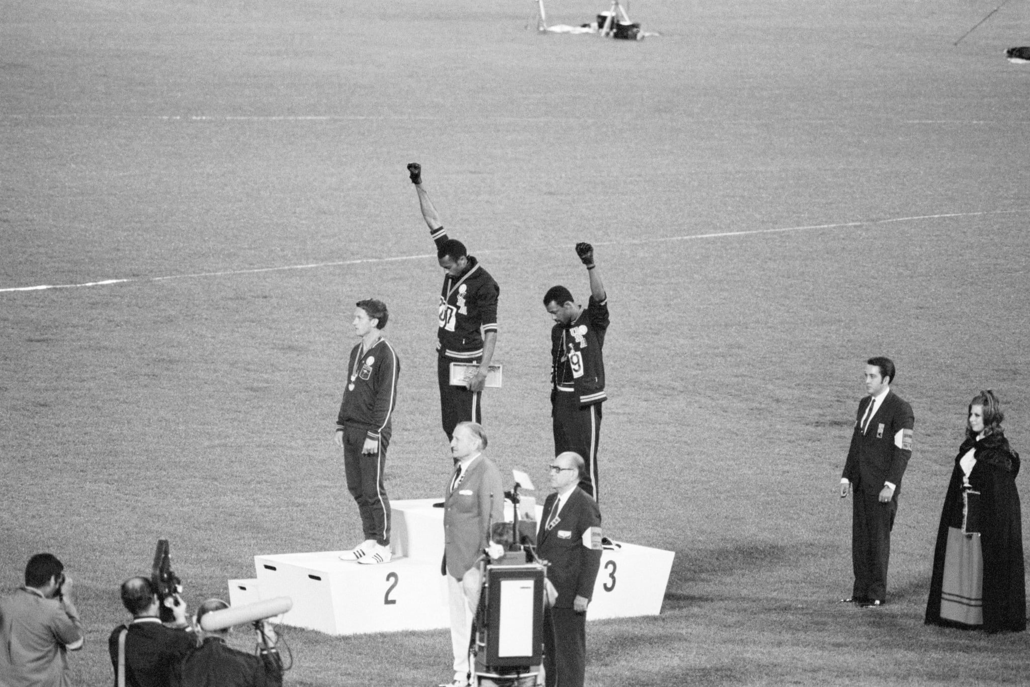 Tommie Smith and John Carlos, gold and bronze medalists in the 200-meter run at the 1968 Olympic Games, engage in a victory stand protest against unfair treatment of blacks in the United States. With heads lowered and black-gloved fists raised in the black power salute, they refuse to recognize the American flag and national anthem. Australian Peter Norman is the silver medalist.