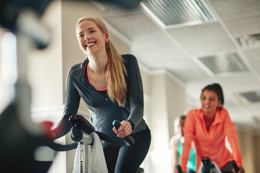 Shot of a young woman working out with an exercise bike in a exercising class at the gym
