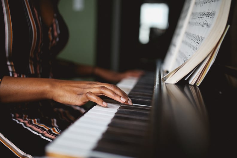 Retro toned, low key portrait of a young mixed race Latina woman practicing piano in her room in Downtown Los Angeles.