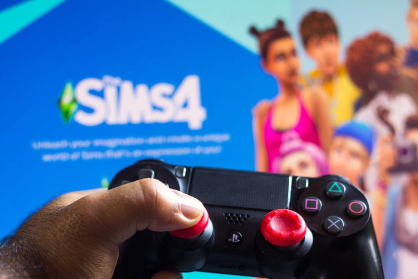 BRAZIL - 2021/05/17: In this photo illustration, a PlayStation (PS) controller and The Sims 4 game logo seen in he background. (Photo Illustration by Rafael Henrique/SOPA Images/LightRocket via Getty Images)