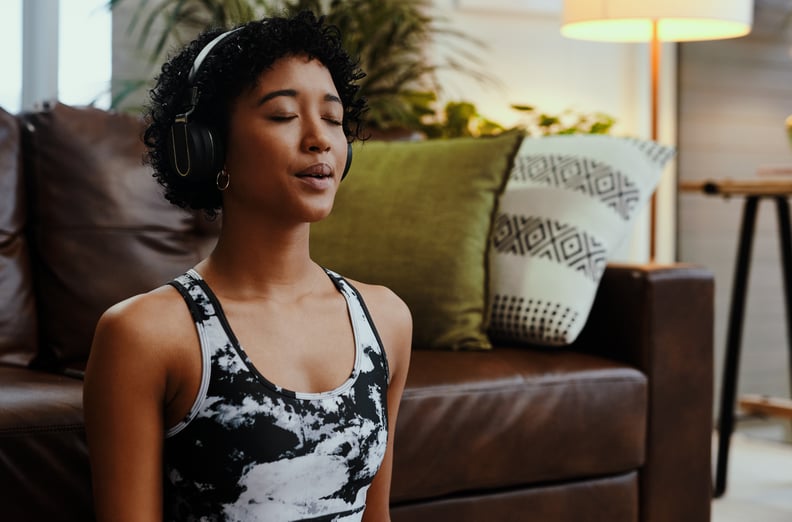Shot of a young woman listening to music while meditating at home