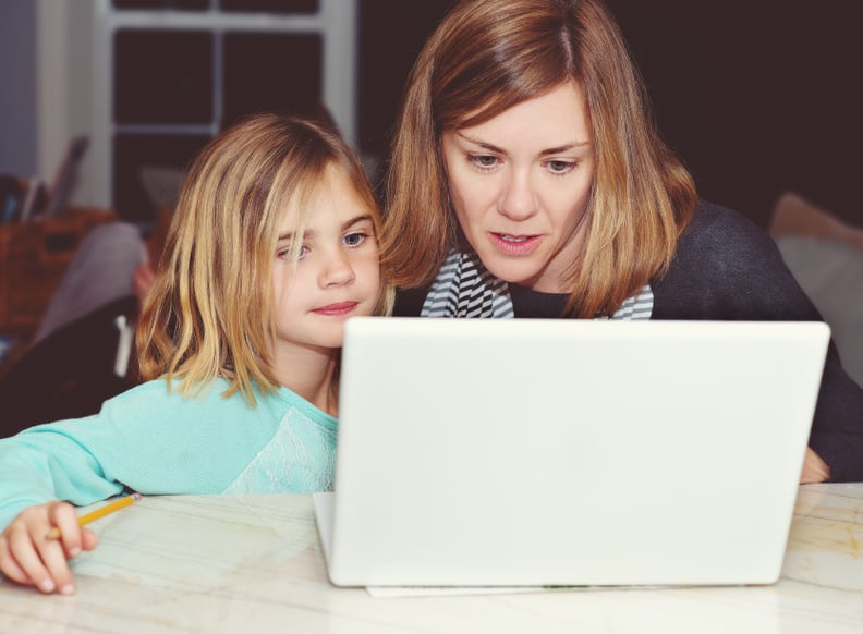 Beautiful mom with her pretty, young daughter using a laptop computer to do homework.