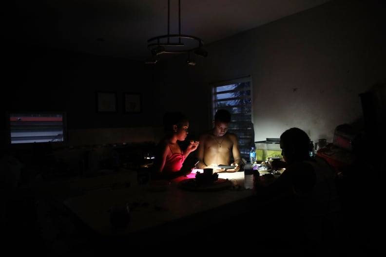 SAN ISIDRO, PUERTO RICO - DECEMBER 21:  Young members of the extended Medina family eat dinner at dusk with light from a cell phone on December 21, 2017 in San Isidro, Puerto Rico. The community was hard-hit by Hurricane Maria and remains mostly without g